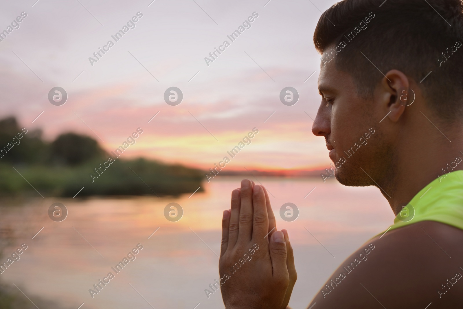 Man meditating near river at sunset. Space for text Photo of Man meditating near river at sunset. Space for text