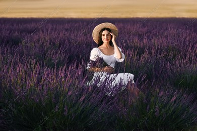Beautiful young woman with bouquet sitting in lavender field at sunset Photo of Beautiful young woman with bouquet sitting in lavender field at sunset