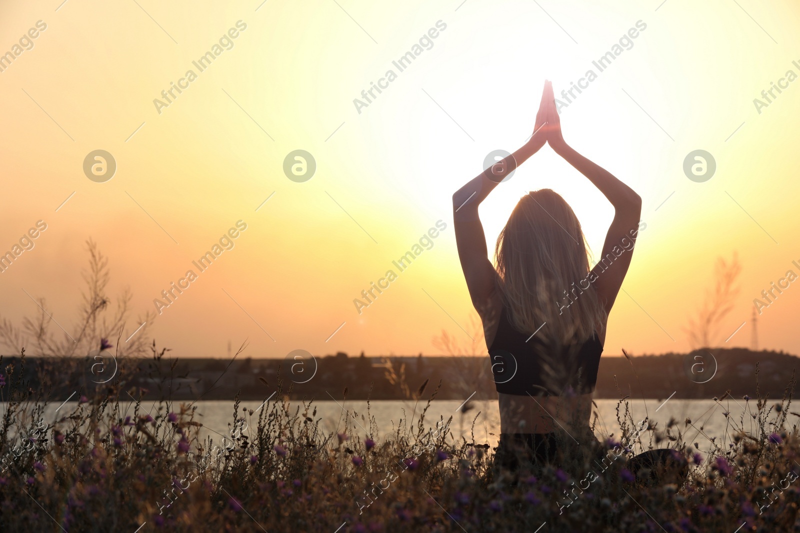 Young woman meditating near river at sunset, back view. Space for text Photo of Young woman meditating near river at sunset, back view. Space for text