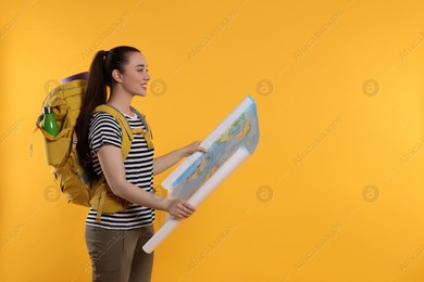 Smiling young woman with backpack and map on orange background, space for text. Active tourism Photo of Smiling young woman with backpack and map on orange background, space for text. Active tourism