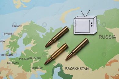 Paper TV and bullets on world map, flat lay. Hybrid warfare concept Photo of Paper TV and bullets on world map, flat lay. Hybrid warfare concept
