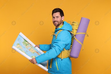 Photo of Happy man with backpack and map on orange background. Active tourism