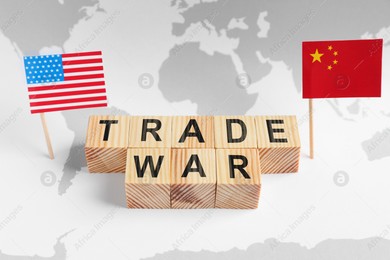 Words Trade War made of wooden cubes, American and Chinese flags on world map Photo of Words Trade War made of wooden cubes, American and Chinese flags on world map