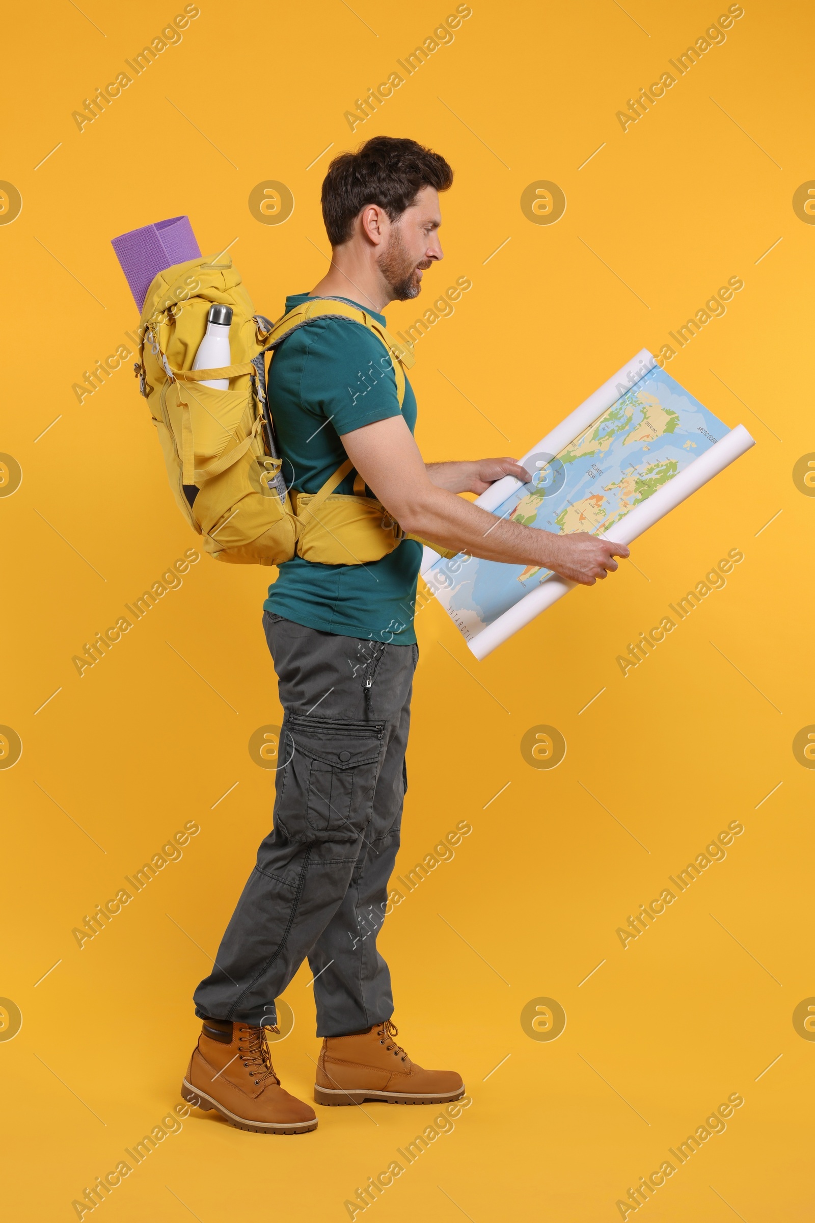 Man with backpack and map on orange background. Active tourism Photo of Man with backpack and map on orange background. Active tourism