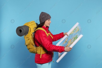 Smiling young woman with backpack and map on light blue background. Active tourism Photo of Smiling young woman with backpack and map on light blue background. Active tourism