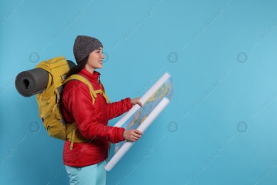 Smiling young woman with backpack and map on light blue background, space for text. Active tourism Photo of Smiling young woman with backpack and map on light blue background, space for text. Active tourism