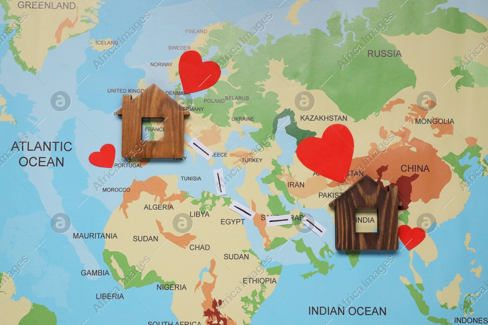 Paper hearts and markings between wooden house models on world map symbolizing connection in long-distance relationship, flat lay Photo of Paper hearts and markings between wooden house models on world map symbolizing connection in long-distance relationship, flat lay