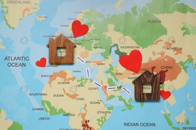 Paper hearts and markings between wooden house models on world map symbolizing connection in long-distance relationship, flat lay Photo of Paper hearts and markings between wooden house models on world map symbolizing connection in long-distance relationship, flat lay