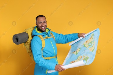Happy tourist with backpack and map on yellow background Photo of Happy tourist with backpack and map on yellow background