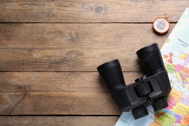 Modern binoculars, map and compass on wooden table, flat lay. Space for text Photo of Modern binoculars, map and compass on wooden table, flat lay. Space for text