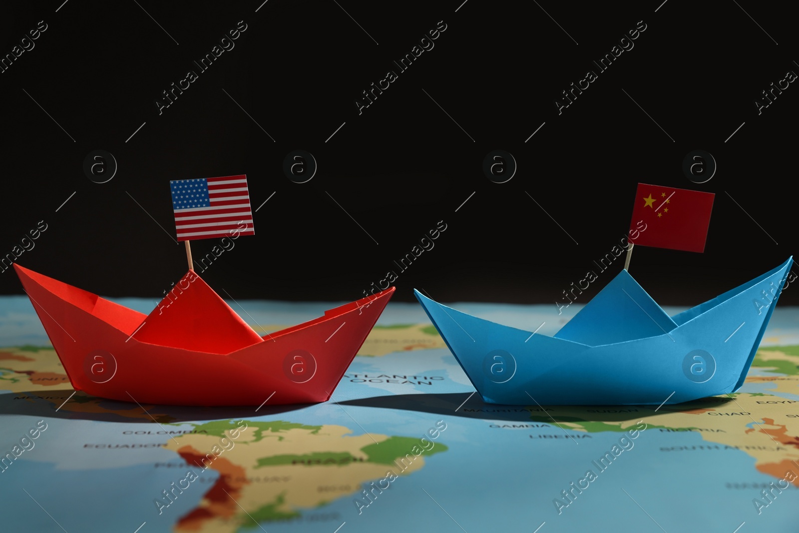 Paper boats with USA and China flags on world map against black background. Trade war concept Photo of Paper boats with USA and China flags on world map against black background. Trade war concept