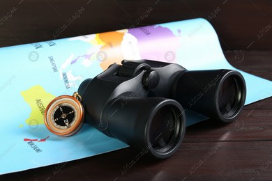Modern binoculars, compass and map on wooden table, closeup Photo of Modern binoculars, compass and map on wooden table, closeup
