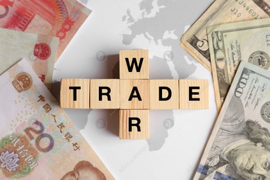 Words Trade war made of wooden cubes, dollar and yuan banknotes on world map, flat lay Photo of Words Trade war made of wooden cubes, dollar and yuan banknotes on world map, flat lay