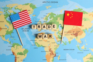 Phrase Trade war made with wooden cubes near USA and China flags on world map, flat lay Photo of Phrase Trade war made with wooden cubes near USA and China flags on world map, flat lay