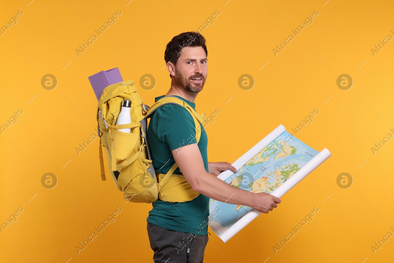 Happy man with backpack and map on orange background. Active tourism Photo of Happy man with backpack and map on orange background. Active tourism