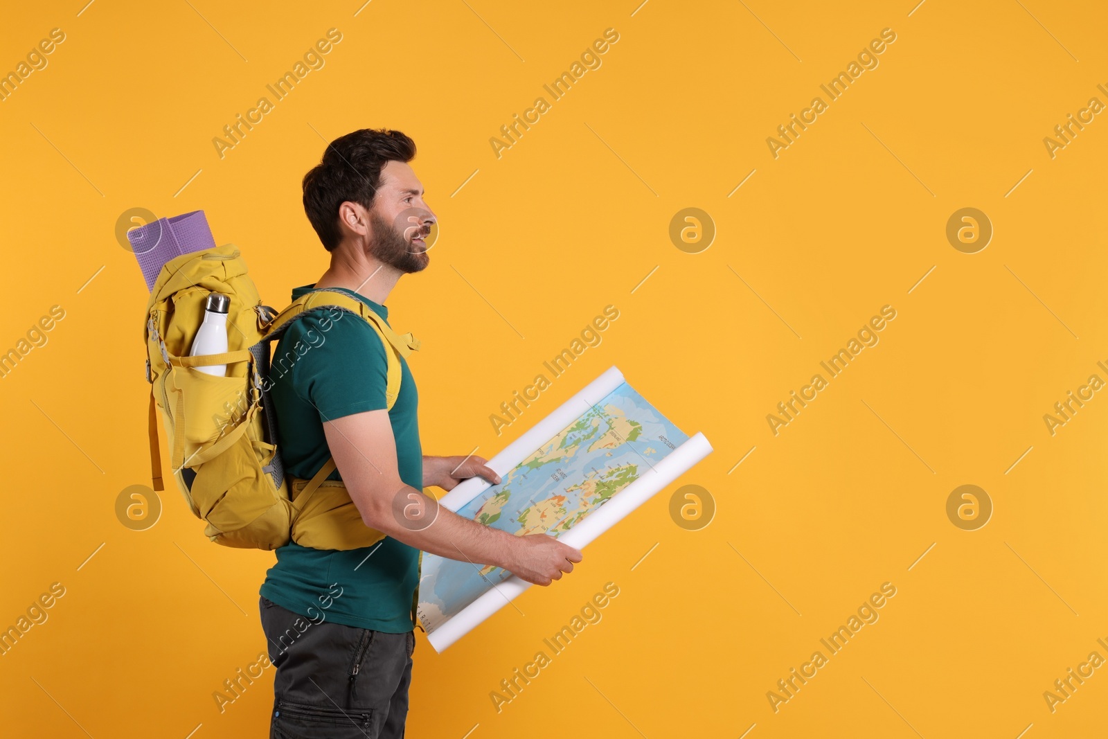 Happy man with backpack and map on orange background, space for text. Active tourism Photo of Happy man with backpack and map on orange background, space for text. Active tourism