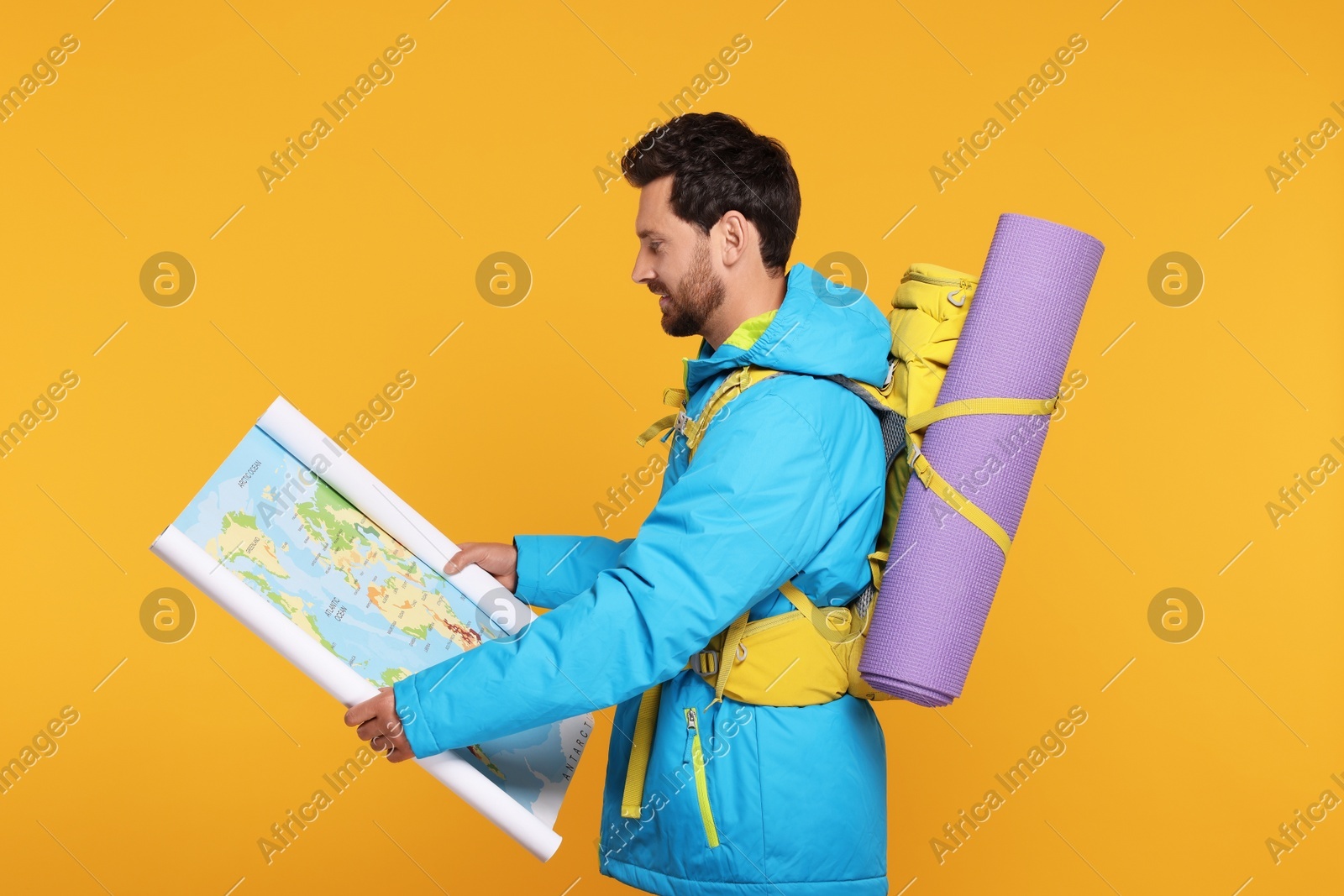 Man with backpack and map on orange background. Active tourism Photo of Man with backpack and map on orange background. Active tourism