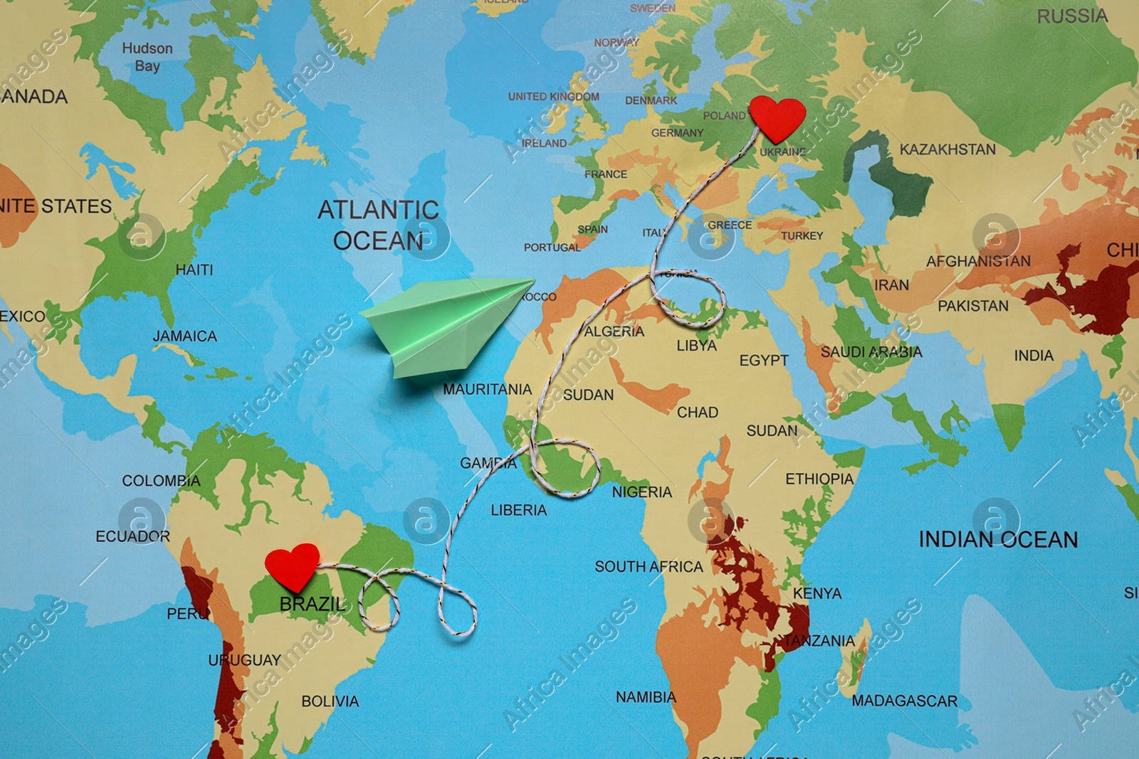Paper plane and decorative cord between two red hearts on world map symbolizing connection in long-distance relationship, flat lay Photo of Paper plane and decorative cord between two red hearts on world map symbolizing connection in long-distance relationship, flat lay
