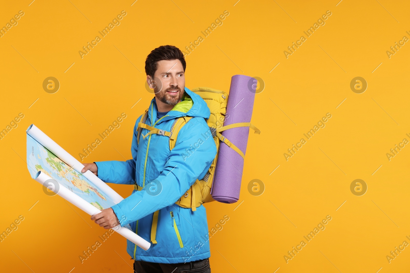 Happy man with backpack and map on orange background, space for text. Active tourism Photo of Happy man with backpack and map on orange background, space for text. Active tourism