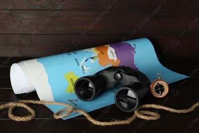 Modern binoculars, rope, compass and map on wooden table Photo of Modern binoculars, rope, compass and map on wooden table