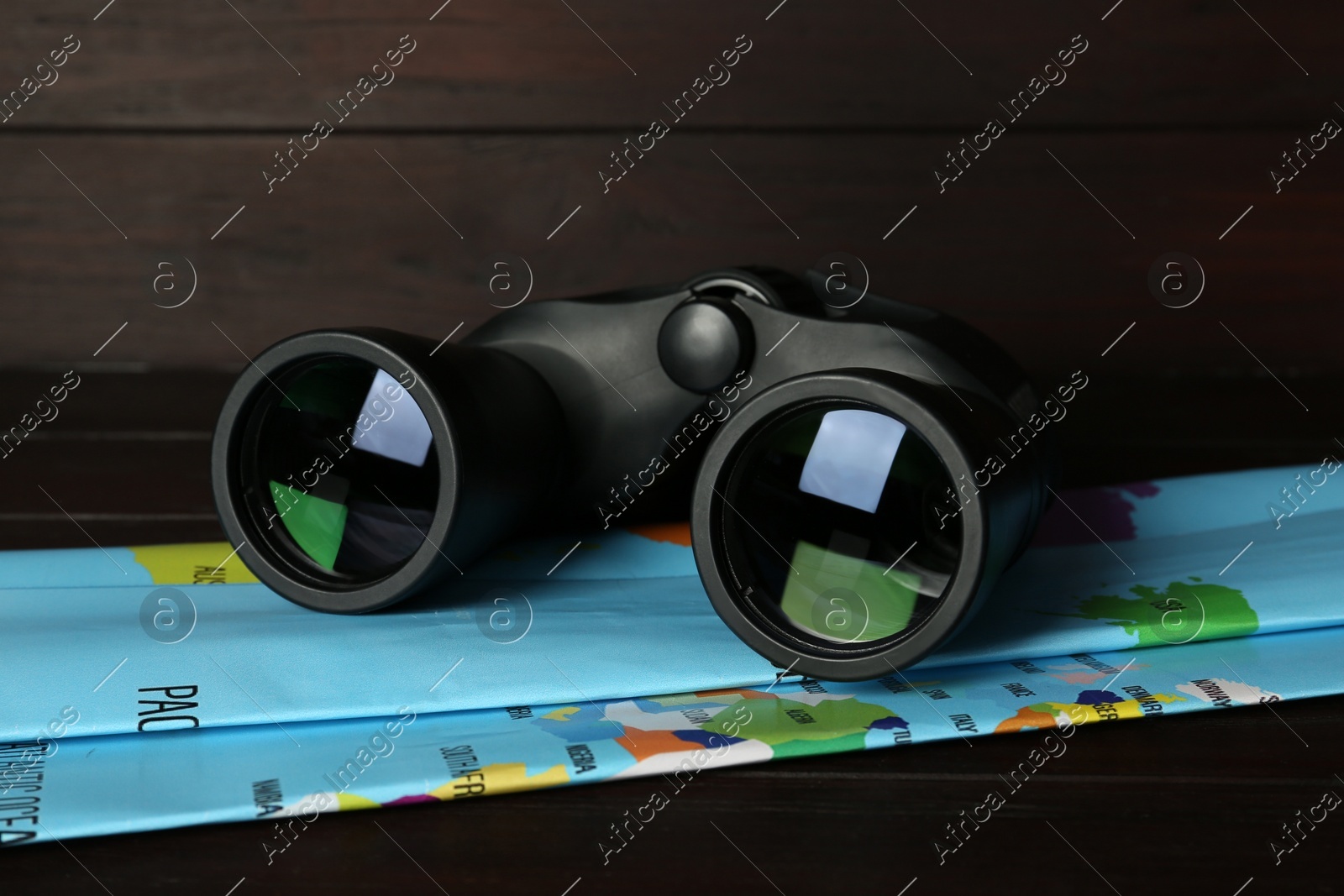 Modern binoculars and map on wooden table, closeup Photo of Modern binoculars and map on wooden table, closeup