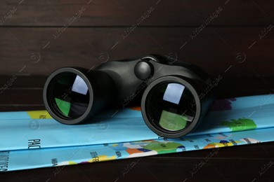 Modern binoculars and map on wooden table, closeup Photo of Modern binoculars and map on wooden table, closeup