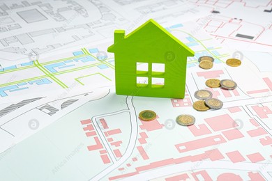Coins and green house model on cadastral maps Photo of Coins and green house model on cadastral maps