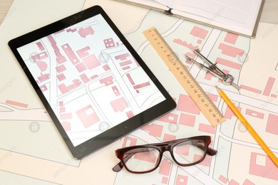 Office stationery, tablet and cadastral maps of territory with buildings on table Photo of Office stationery, tablet and cadastral maps of territory with buildings on table