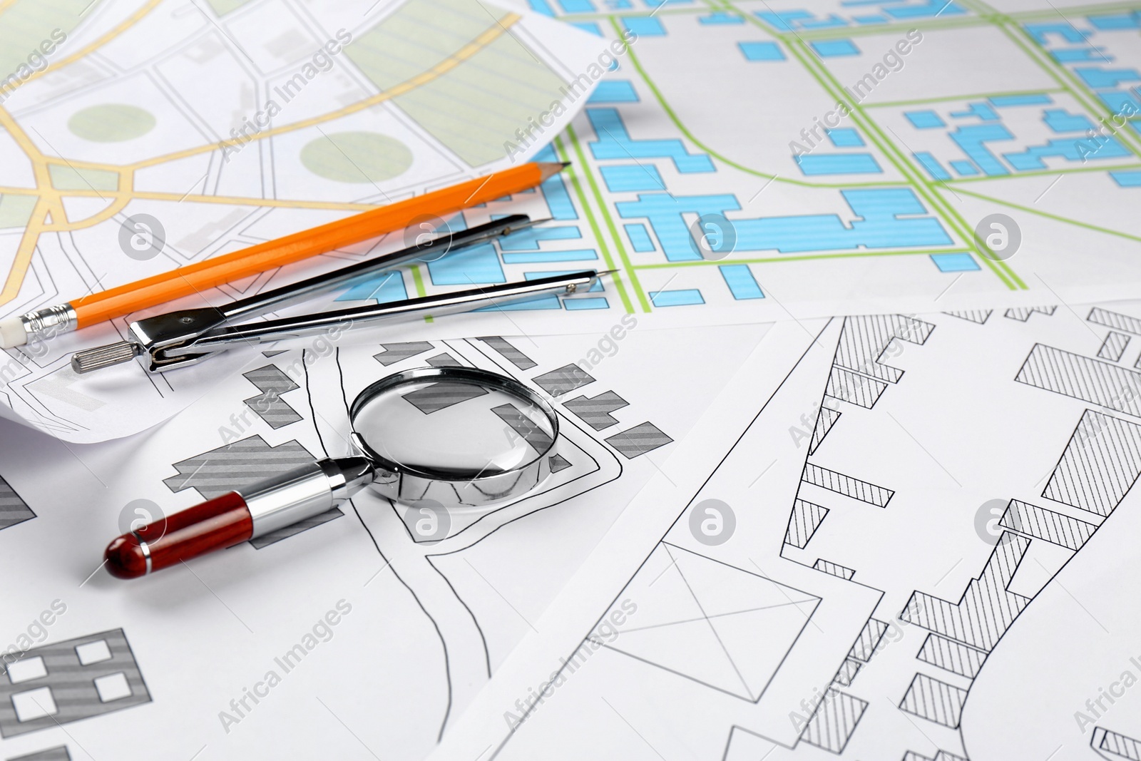 Office stationery and magnifying glass on cadastral maps of territory with buildings Photo of Office stationery and magnifying glass on cadastral maps of territory with buildings
