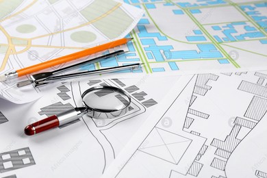 Office stationery and magnifying glass on cadastral maps of territory with buildings Photo of Office stationery and magnifying glass on cadastral maps of territory with buildings