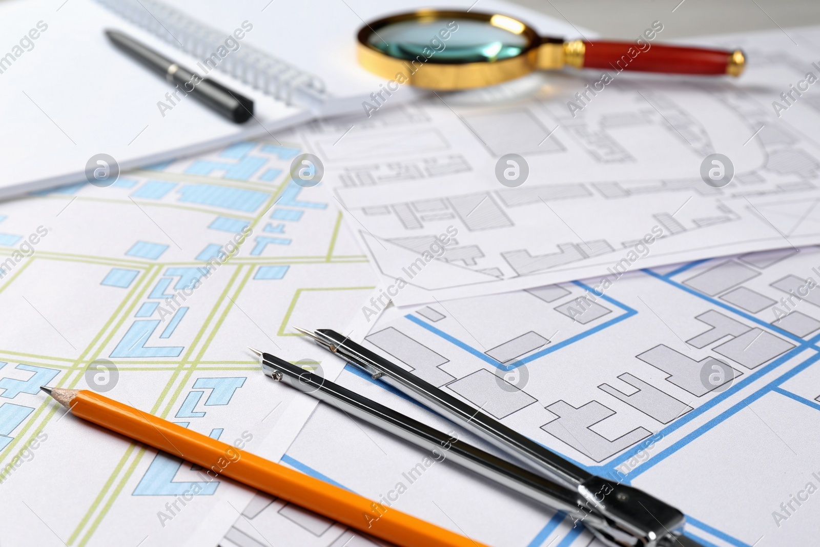 Office stationery and cadastral maps of territory with buildings on table Photo of Office stationery and cadastral maps of territory with buildings on table