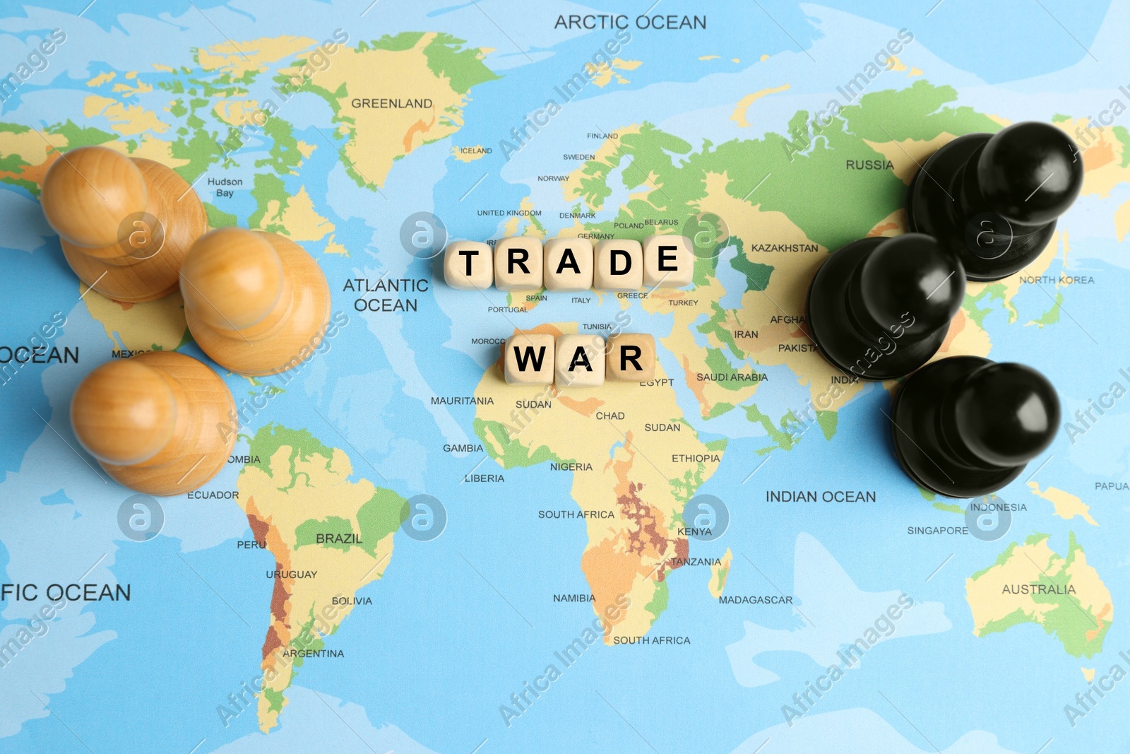 Wooden cubes with phrase Trade war and chess pieces on world map, flat lay Photo of Wooden cubes with phrase Trade war and chess pieces on world map, flat lay