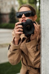 Private detective with modern camera spying outdoors, focus on lens Photo of Private detective with modern camera spying outdoors, focus on lens