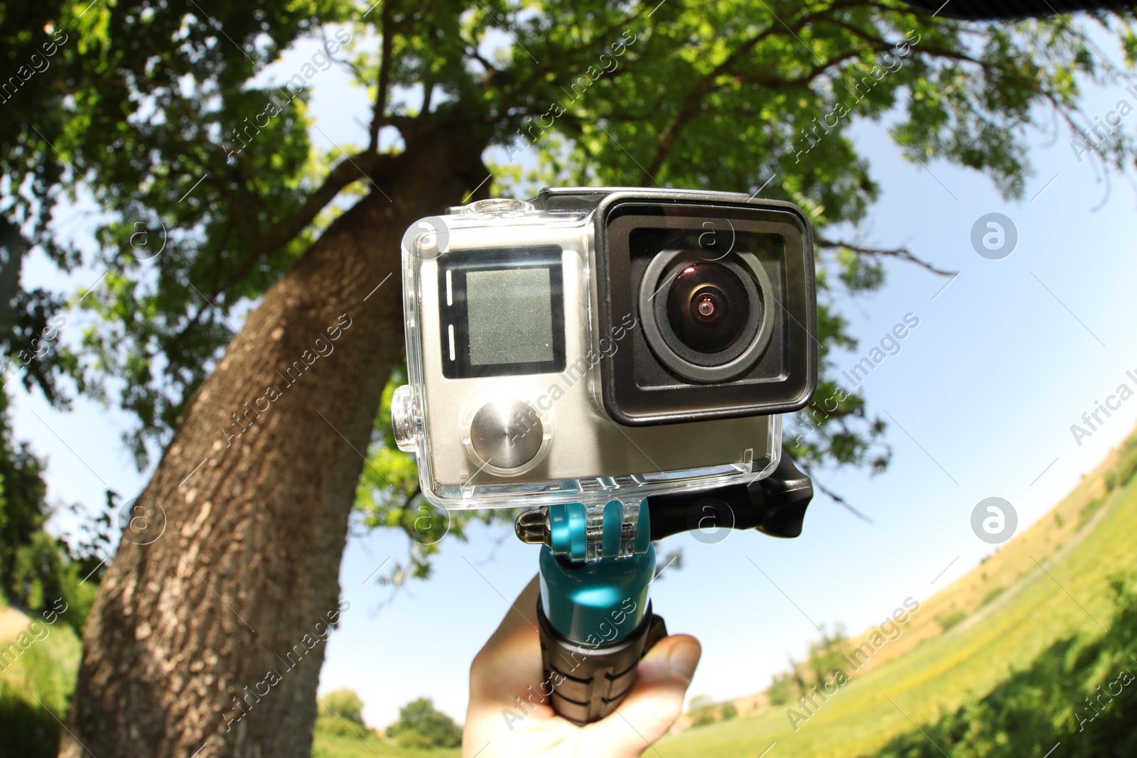 Man with modern action camera and monopod outdoors, closeup. Fisheye lens effect Photo of Man with modern action camera and monopod outdoors, closeup. Fisheye lens effect