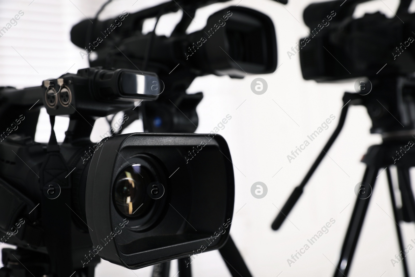 Modern video camera indoors, focus on lens. Professional media equipment for broadcasting event Photo of Modern video camera indoors, focus on lens. Professional media equipment for broadcasting event