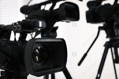 Modern video camera indoors, focus on lens. Professional media equipment for broadcasting event Photo of Modern video camera indoors, focus on lens. Professional media equipment for broadcasting event