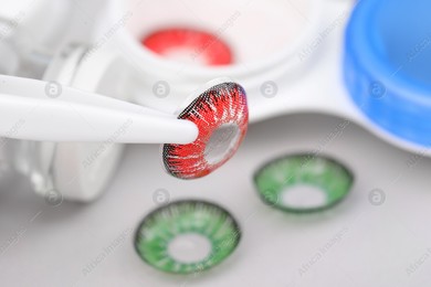 Tweezers with red contact lens on blurred background, closeup. Space for text Photo of Tweezers with red contact lens on blurred background, closeup. Space for text