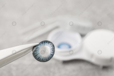 Tweezers with blue contact lens over table, closeup. Space for text Photo of Tweezers with blue contact lens over table, closeup. Space for text