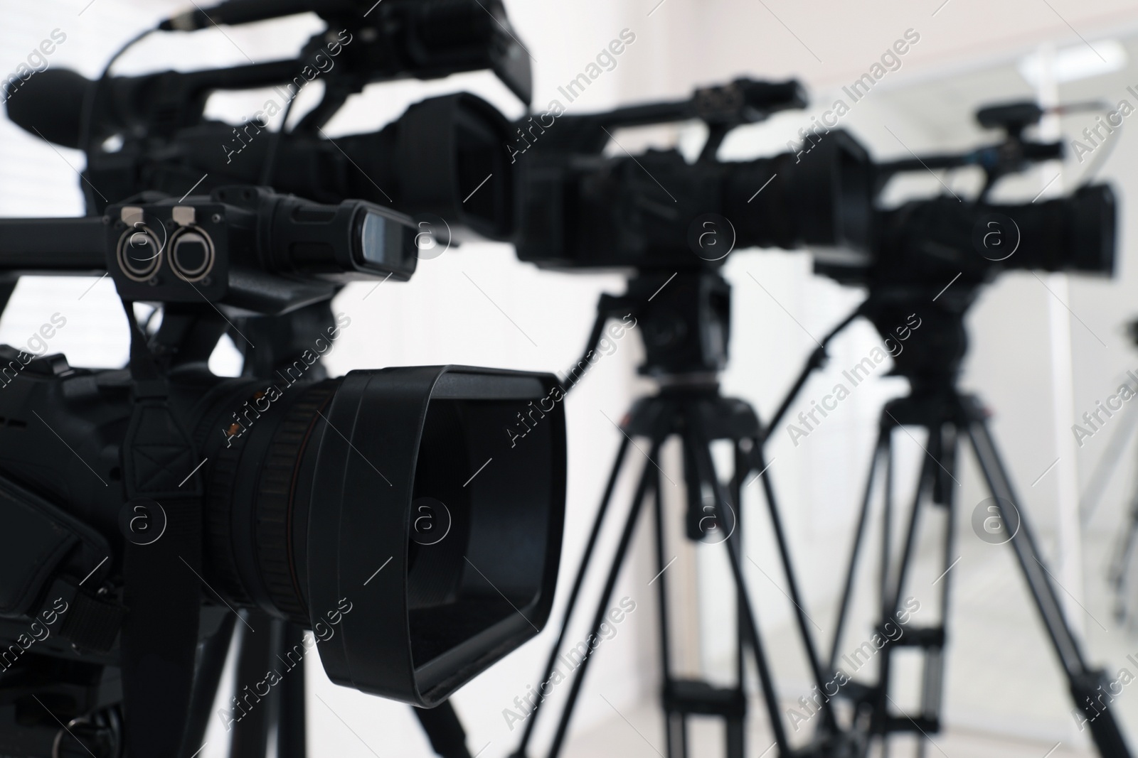 Modern video camera indoors, focus on lens. Professional media equipment for broadcasting event Photo of Modern video camera indoors, focus on lens. Professional media equipment for broadcasting event