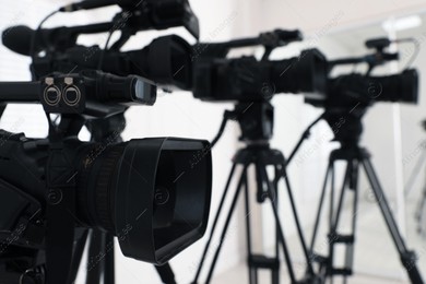Modern video camera indoors, focus on lens. Professional media equipment for broadcasting event Photo of Modern video camera indoors, focus on lens. Professional media equipment for broadcasting event