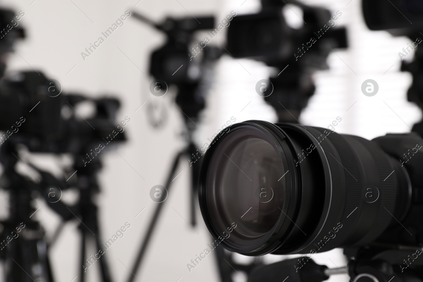 Modern video camera indoors, focus on lens. Professional media equipment for broadcasting event Photo of Modern video camera indoors, focus on lens. Professional media equipment for broadcasting event