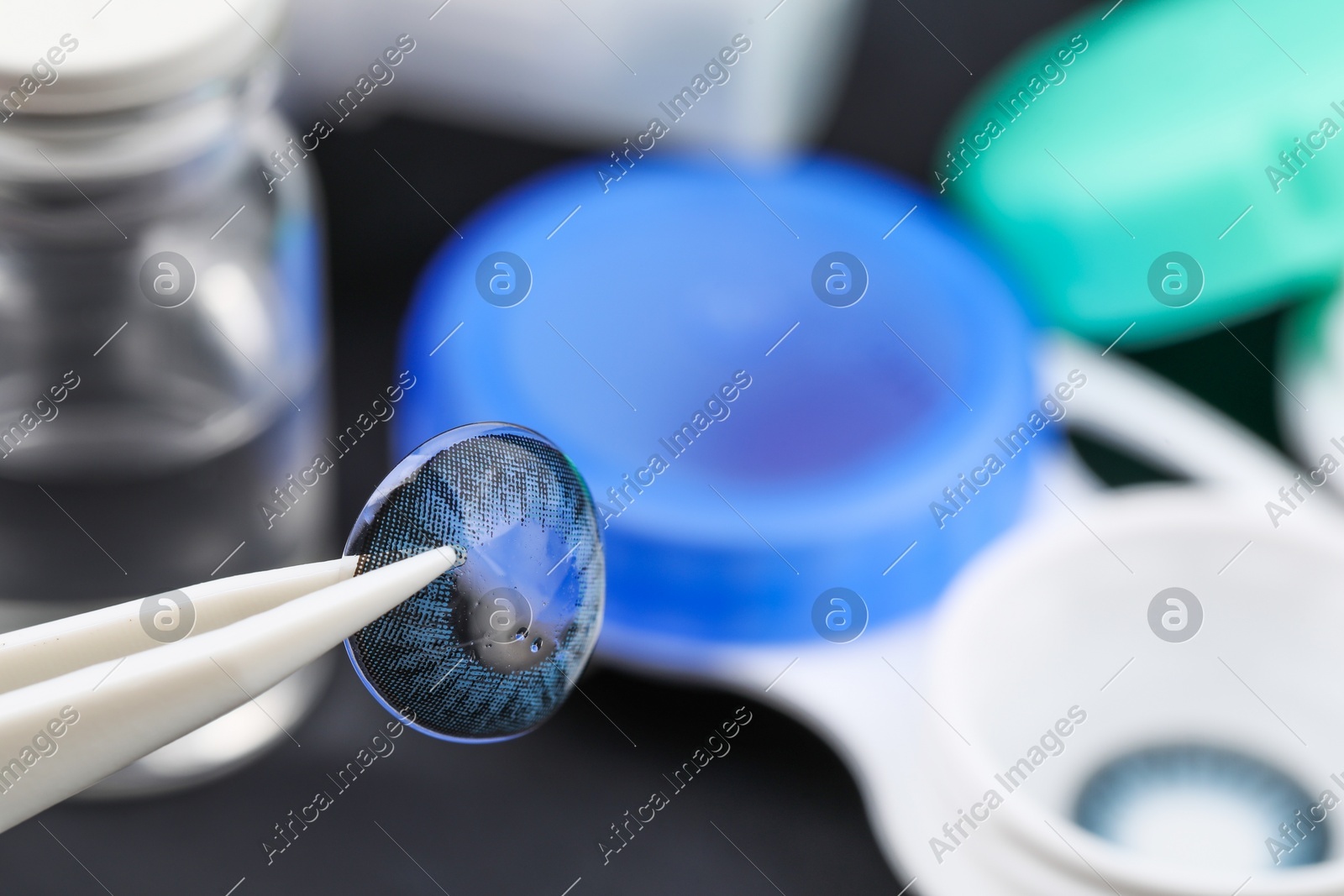 Tweezers with color contact lens over table, closeup. Space for text Photo of Tweezers with color contact lens over table, closeup. Space for text