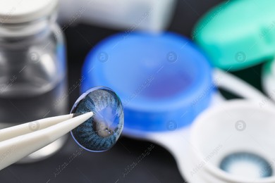 Tweezers with color contact lens over table, closeup. Space for text Photo of Tweezers with color contact lens over table, closeup. Space for text