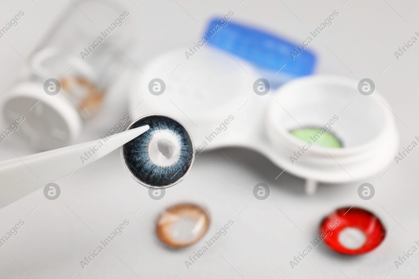 Tweezers with blue contact lens over table, closeup. Space for text Photo of Tweezers with blue contact lens over table, closeup. Space for text