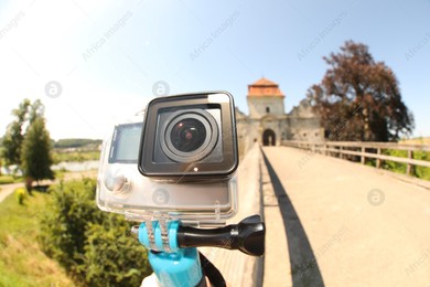 Modern action camera with monopod outdoors, closeup. Fisheye lens effect Photo of Modern action camera with monopod outdoors, closeup. Fisheye lens effect