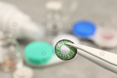 Tweezers with green contact lens over table, closeup. Space for text Photo of Tweezers with green contact lens over table, closeup. Space for text