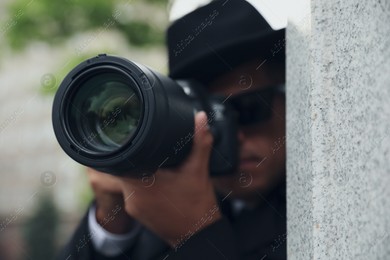 Private detective with modern camera spying outdoors, focus on lens Photo of Private detective with modern camera spying outdoors, focus on lens