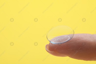 Woman with contact lens on yellow background, closeup. Space for text Photo of Woman with contact lens on yellow background, closeup. Space for text