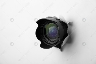Hidden camera lens through torn hole in white paper Photo of Hidden camera lens through torn hole in white paper