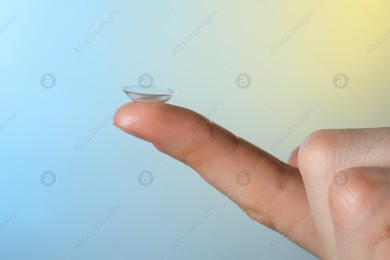 Woman holding contact lens on color background, closeup Photo of Woman holding contact lens on color background, closeup